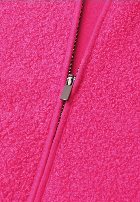 Nahaufnahme eines leuchtend pinken Reißverschlusses auf flauschigem Fleece-Stoff.