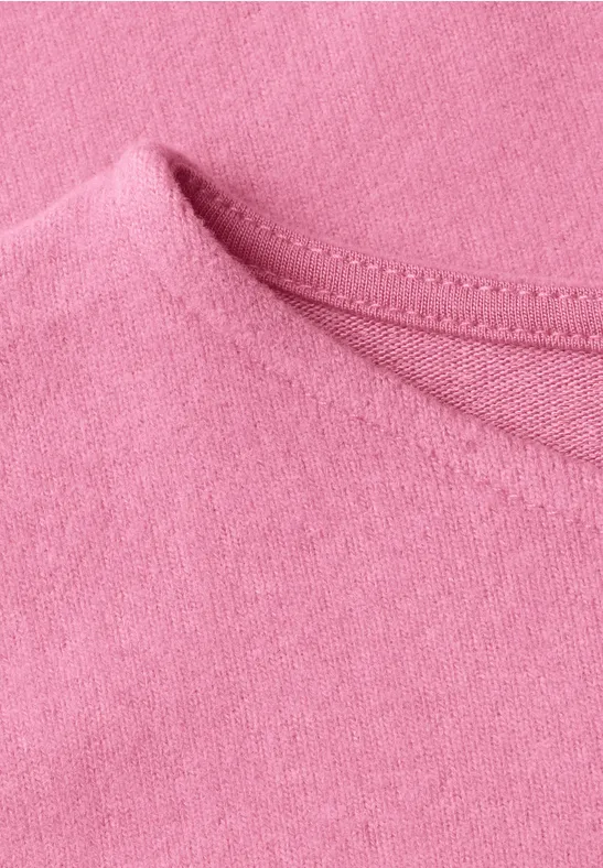 Gros plan sur l'encolure d'un t-shirt rose en tissu doux.