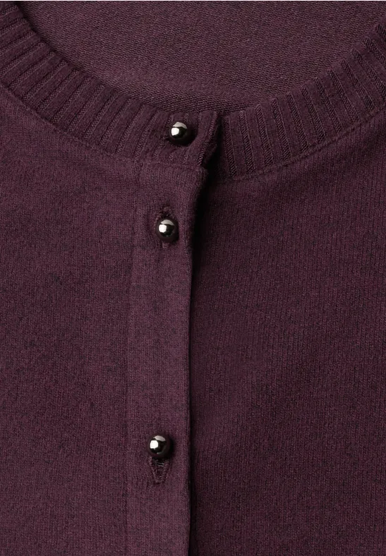 Nahaufnahme eines violetten Cardigans mit kleinen schwarzen Perlenknöpfen.