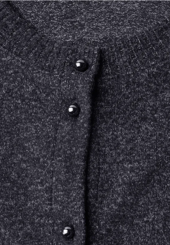 Close-up van een grijze gebreide cardigan met zwarte bolvormige knopen.
