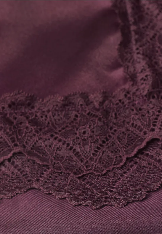 Nahaufnahme von dunkelrotem Satin mit floraler Spitze