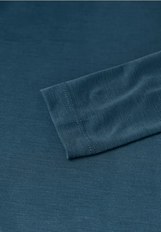 Nahaufnahme eines dunkelgrünen langärmligen Shirts mit geripptem Ärmelbündchen auf einfarbigem Untergrund.