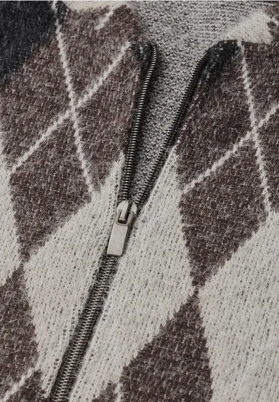 Gros plan d'un pull tricoté à motif losange beige avec une fermeture éclair centrale.