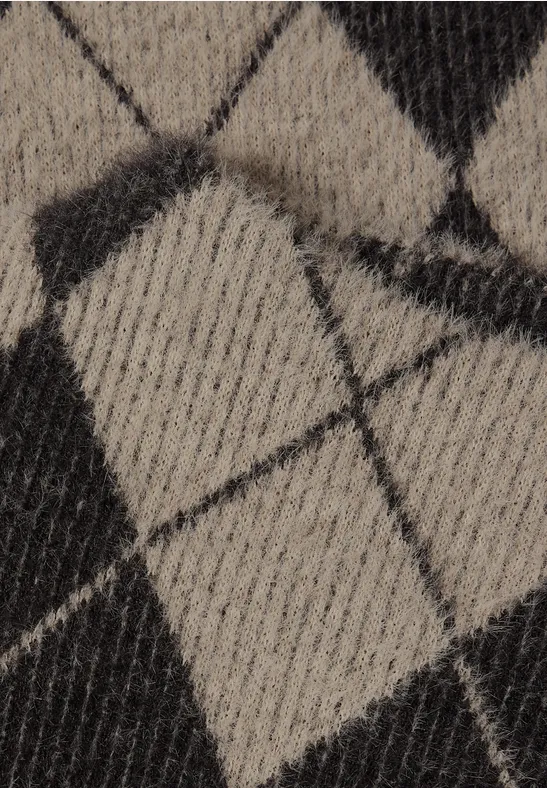 Nahaufnahme eines Strickstoffs mit schwarz-beigem Rautenmuster.