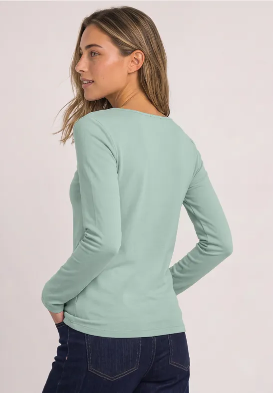 Frau von hinten in mintgrünem Langarmshirt und Jeans.