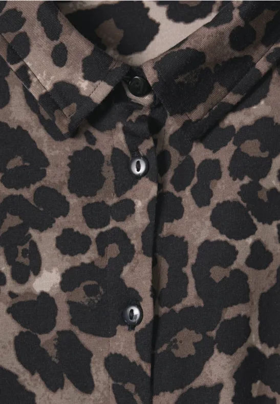 Nahe Ansicht einer blusigen Hemdjacke mit Knöpfen und olivbraunem Leopardenmuster.