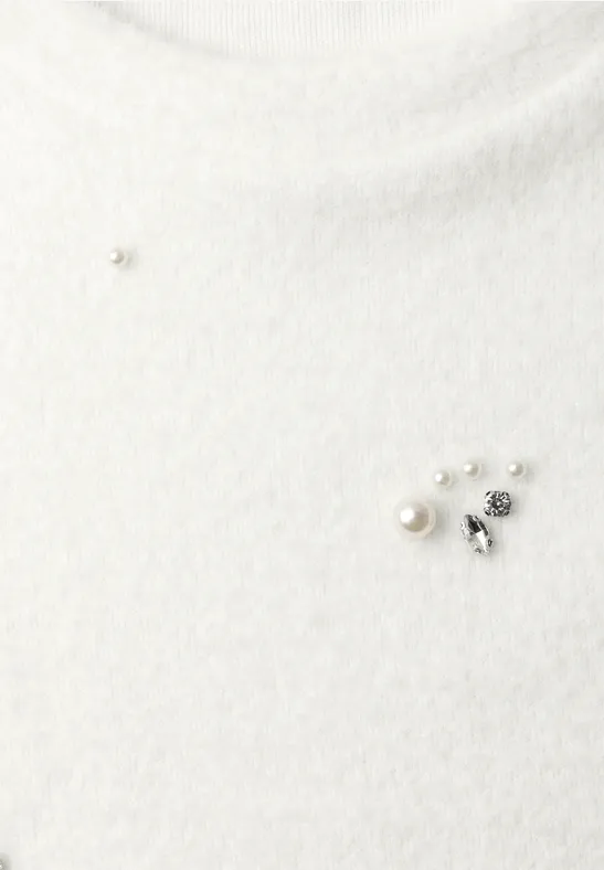 Weißer, flauschiger Rollkragenpullover mit dekorativer Brosche aus Perlen und silbernen Nieten