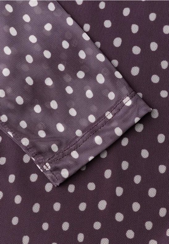 Nahaufnahme eines violetten Stoffes mit weißen Polka-Dots und einer abgenähten Kante einer Manschette.