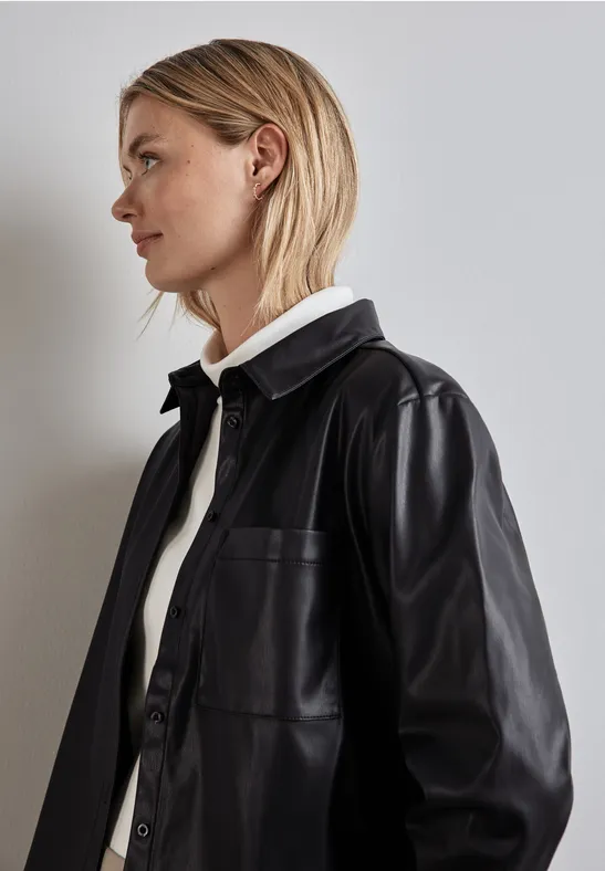 Frau mit blonden Haaren trägt schwarze Lederjacke und weißen Rollkragen.