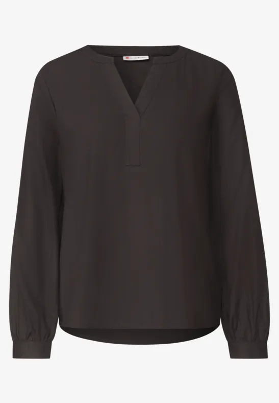 Zwarte, losvallende blouse met V-hals en lange mouwen.