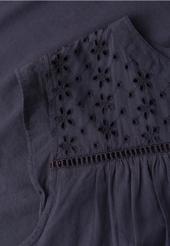 Dunkelblaues Oberteil mit floraler Lochstickerei im Brustbereich und sanften Falten.