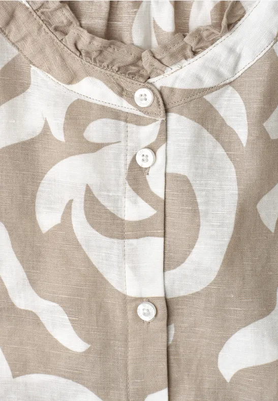 Gros plan sur un chemisier beige à motifs floraux blancs avec boutons assortis.