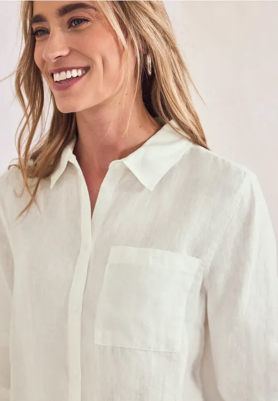 Vrouw draagt een witte linnen blouse met kraag en borstzak.