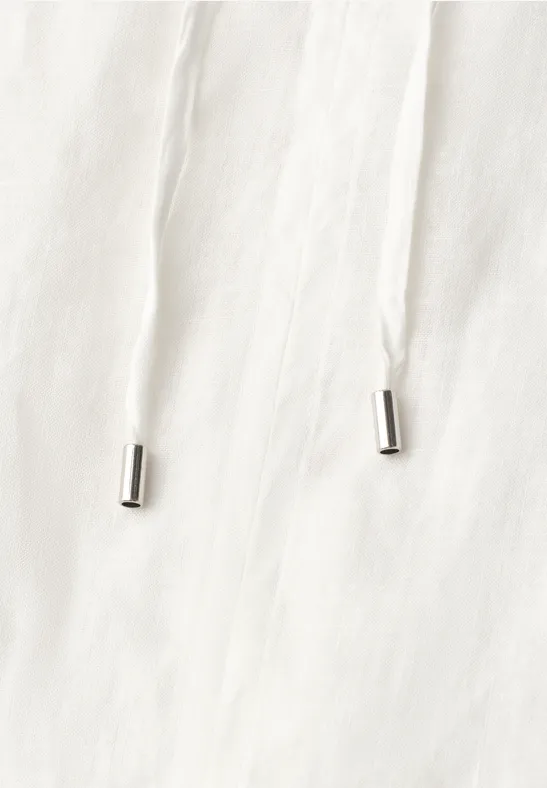 Weiße Kordel mit silbernen Endkappen auf hellem Stoff.