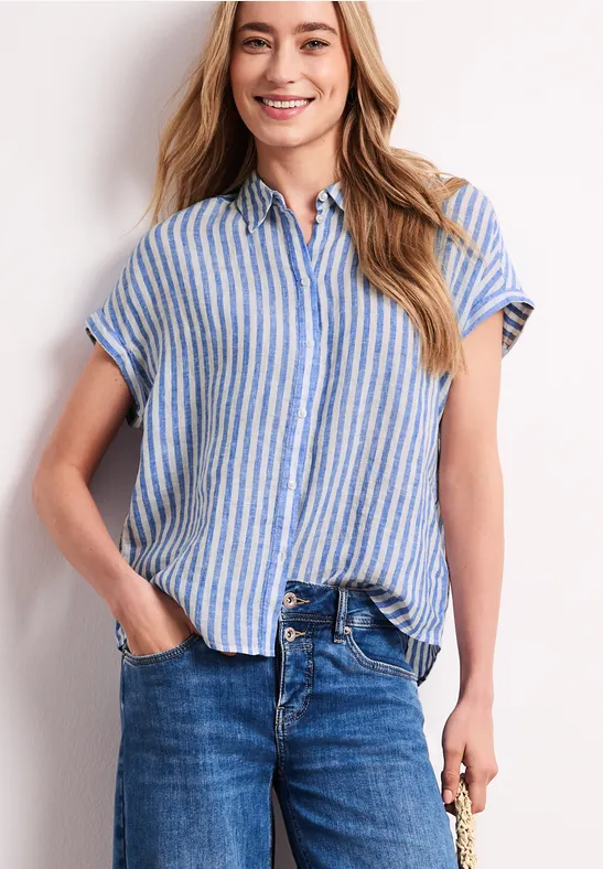 Vrouw in blauw-wit gestreept kort shirt en hoge taille jeans, één hand in de zak, andere houdt sleutel.