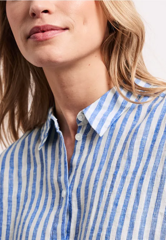 Close-up van een vrouw in een blauw-wit gestreept linnen overhemd, gezicht deels zichtbaar.