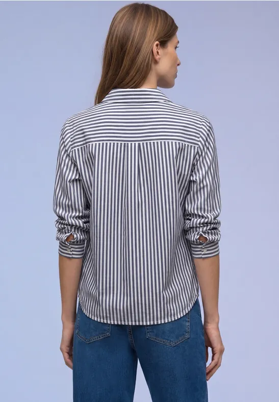 Eine Frau mit gestreiftem Hemd und Jeans, Rücken zur Kamera.