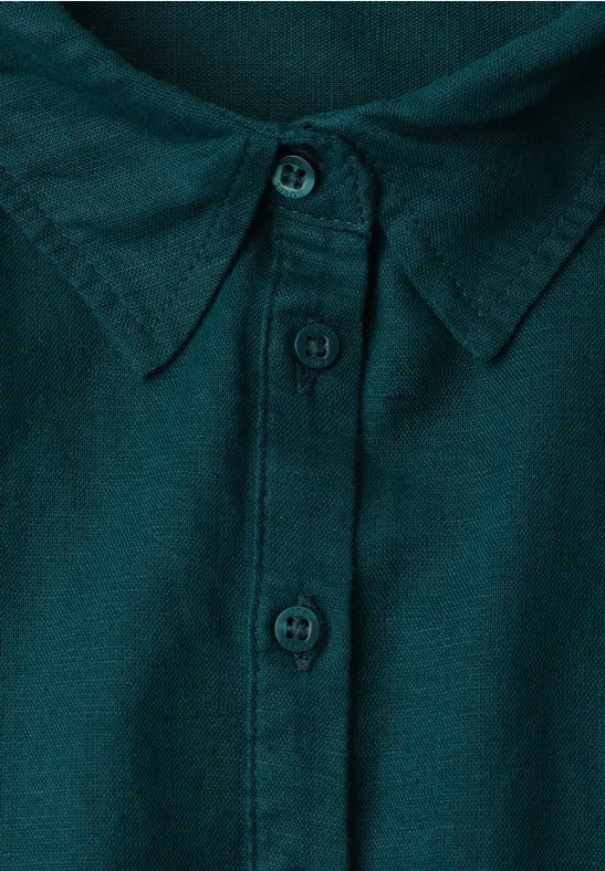 Nahaufnahme eines dunkelgrünen Hemdkragens mit Knopfleiste und drei sichtbaren Knöpfen.