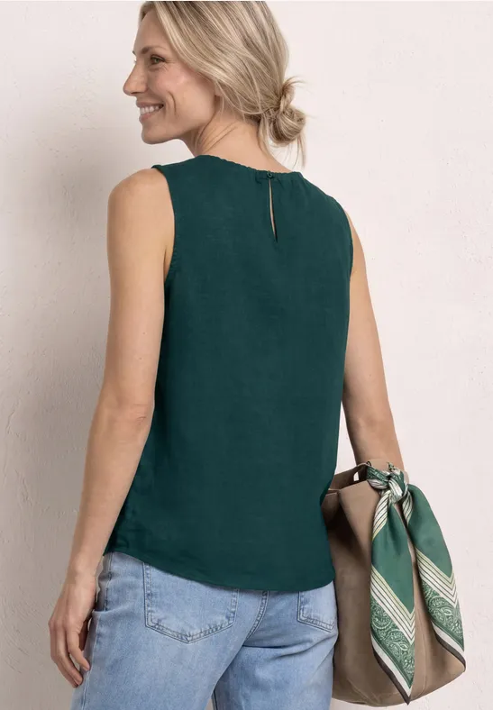 Achteraanzicht van vrouw in donkergroen mouwloos topje, blauwe jeans en tas met groen sjaaltje.