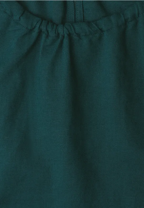 Close-up van een donkergroene, elastisch geplooide stof met naad en fijne textuur.