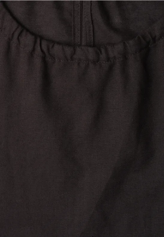 Close-up van een zwart kledingstuk van soepel stof met elastische zoom.