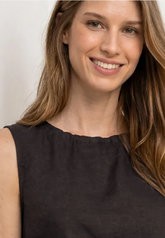 Een vrouw met lichtbruin lang haar draagt een zwart mouwloos bovenstuk. Gezicht onscherp.