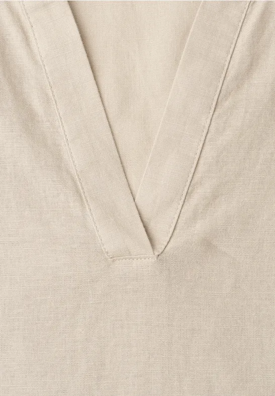 Beige linnenstof met een V-vormige naad of halslijn.