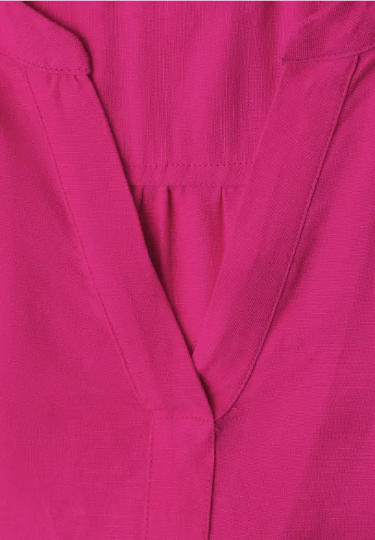 Close-up van een felroze kledingstuk met zichtbare naad bij de V-hals.