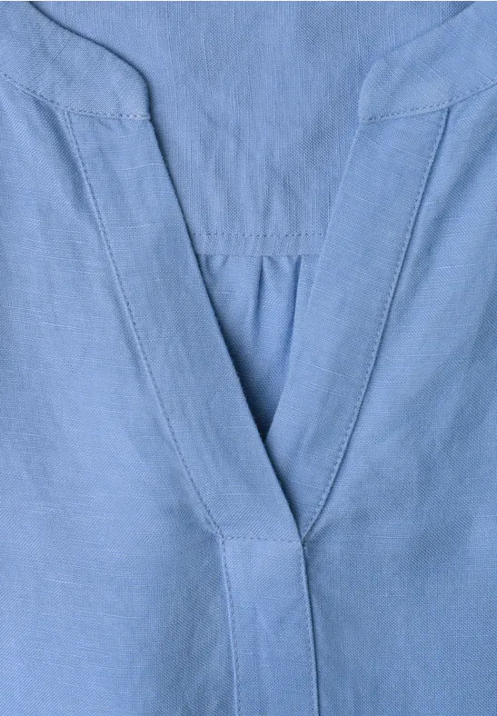 Lichtblauwe V-hals met fijne naden, waarschijnlijk onderdeel van een bovenstuk.