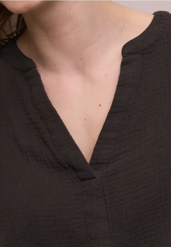 Ausschnitt einer Person in schwarzem V-Ausschnitt-Shirt, Fokus auf Hals und Schlüsselbein.
