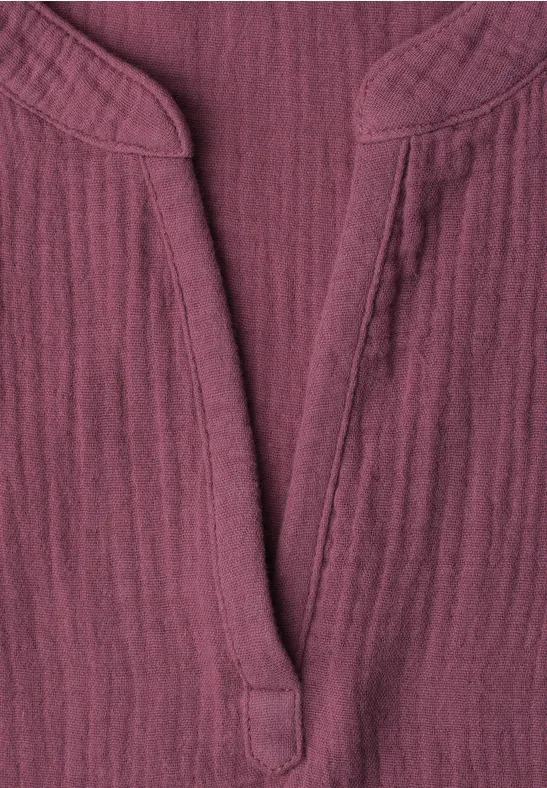 Nahaufnahme eines bordeauxroten, strukturierten Baumwollshirts mit V-Ausschnitt und Stehkragen.