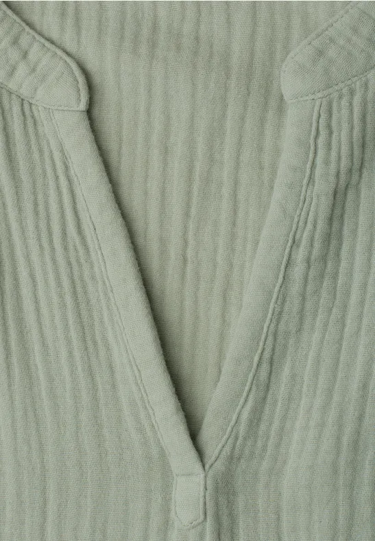 Grünes, geripptes V-Ausschnitt-Oberteil aus weichem Stoff.