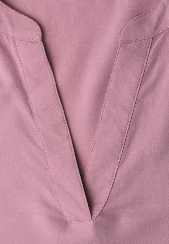 Close-up van een roze V-hals van stof met zichtbare naden en subtiele textuur.