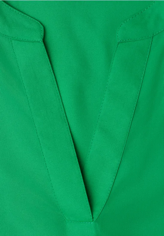 Groen shirt met diepe V-hals, zichtbare stiksels en luchtige stof.