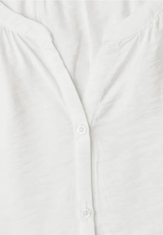 Close-up van een wit T-shirt met V-hals en twee witte knopen.