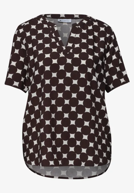Blouse noire à motif de cercles blancs, col V et manches courtes.