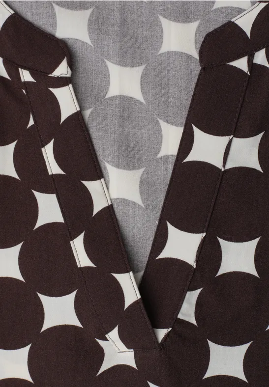 Haut cache-cœur brun foncé à motif géométrique blanc en forme d’étoile circulaire.