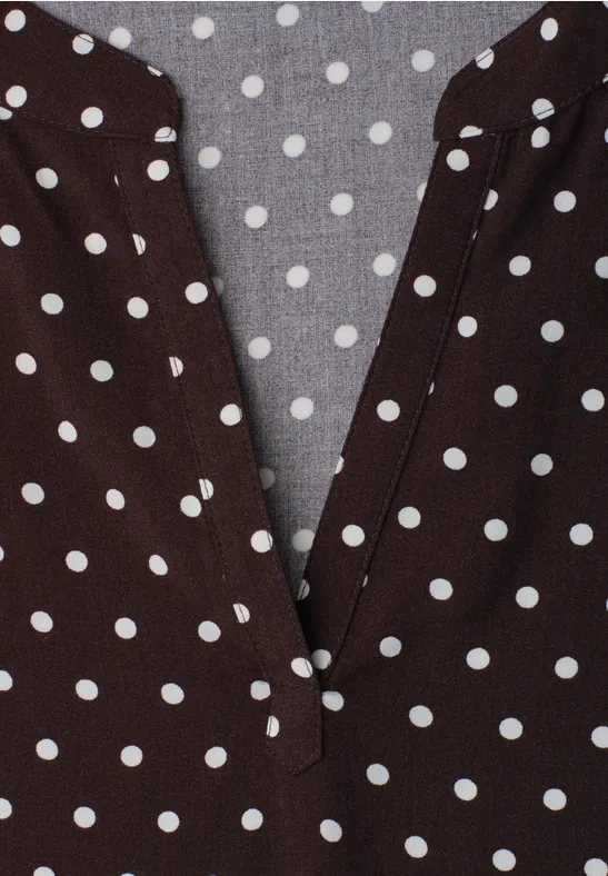 Braunes Polka-Dot-Oberteil mit weiß gepunktetem Muster und V-Ausschnitt.