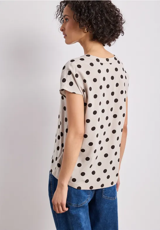 Vrouw van achter gezien met een polkadotshirt en spijkerbroek
