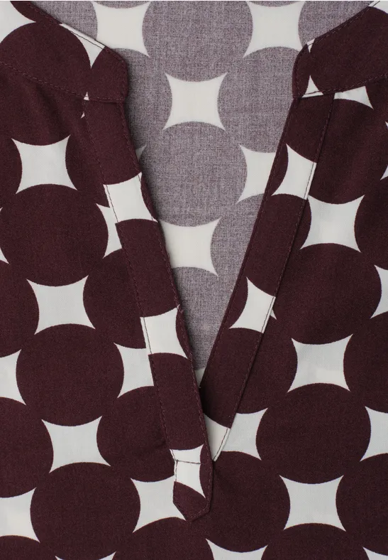 Dunkelbraunes Kleidungsstück mit großem geometrischem Weiß-Kreis-Stern-Muster und V-Ausschnitt