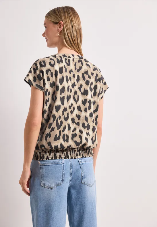 Vrouw van achteren in spijkerbroek en kort mouwen top met panterprint.