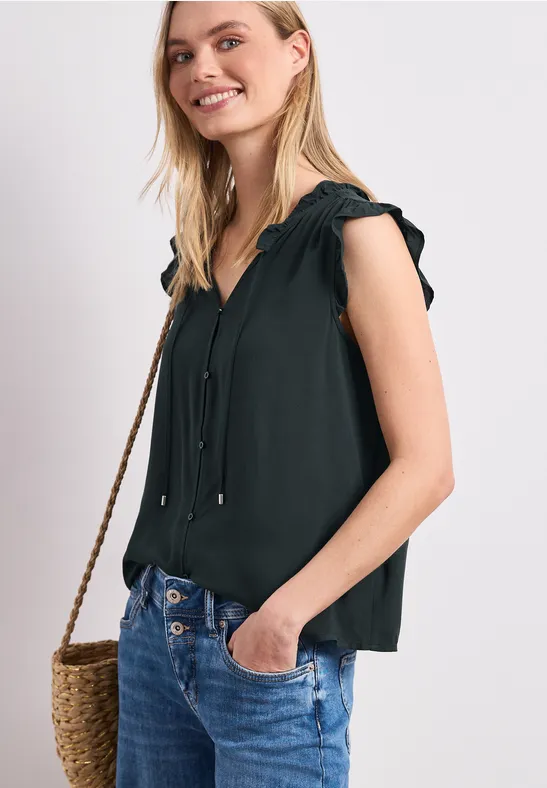 Vrouw met zwarte mouwloze top, spijkerbroek en strozak.