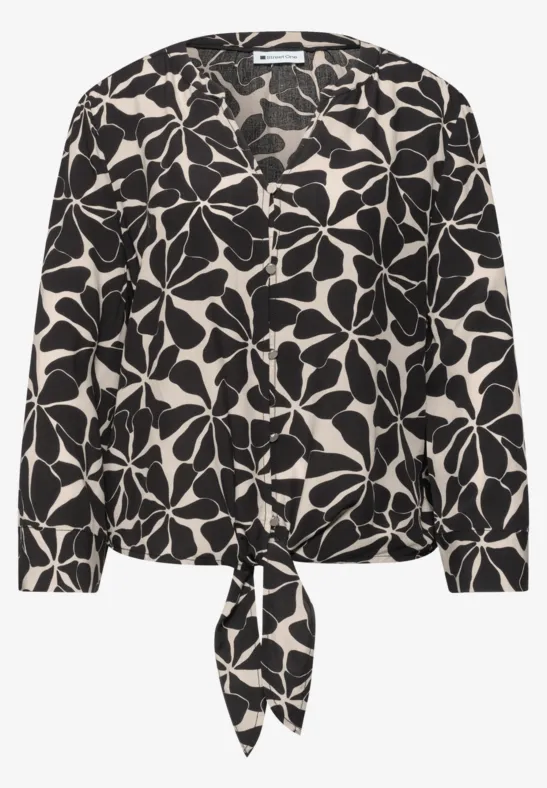 Schwarz-weiße Bluse mit großem Blumenmuster und Knoten am Saum.