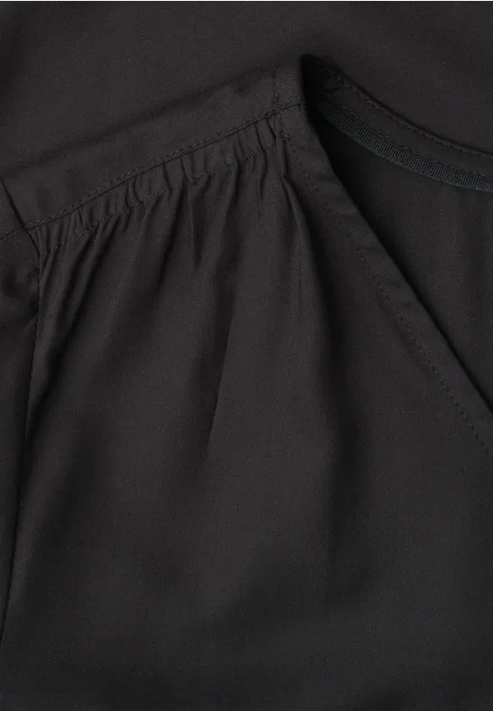 Nahaufnahme eines schwarzen Kleidungsstücks mit Tasche und feinen Nähten