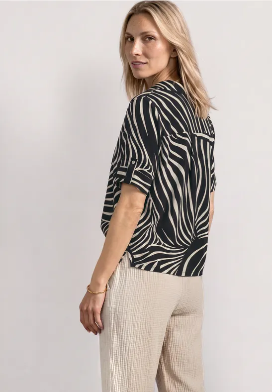 Vrouw zijwaarts met een zwart-wit gestreept shirt en een beige, ruime broek
