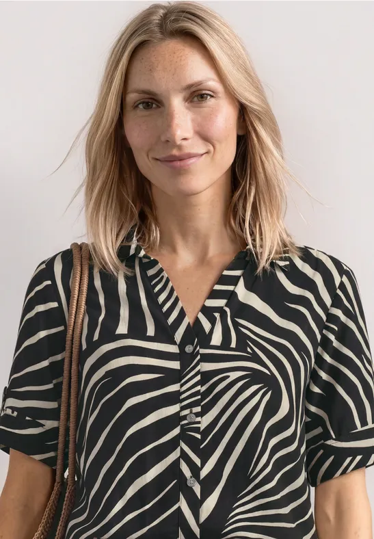 Vrouw met een zwart-wit gestreept zebra-shirt met korte mouwen en een schoudertas.