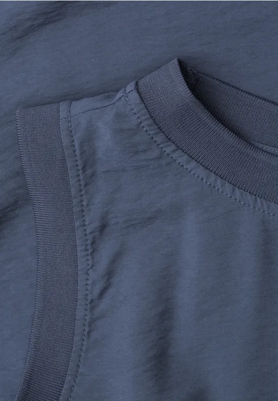 Zbliżenie granatowego T-shirtu, widoczne szwy przy dekolcie oraz struktura materiału.