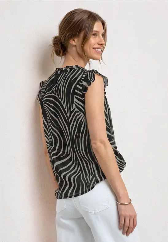 Vrouw van achteren in een gestreept top en witte broek, met haar in een knot.