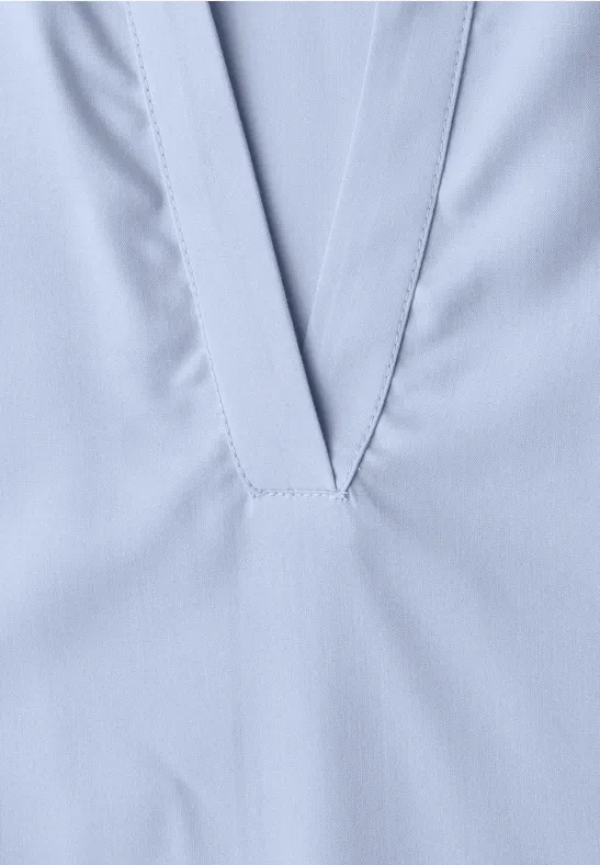 Close-up van een lichtblauwe V-hals met nette naden op gladde stof.