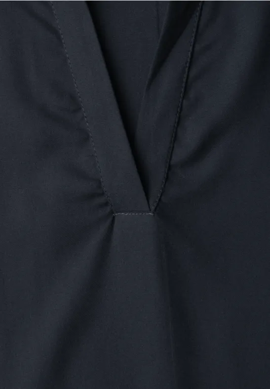 Detail van een donker kledingstuk met V-opening en siernaad.